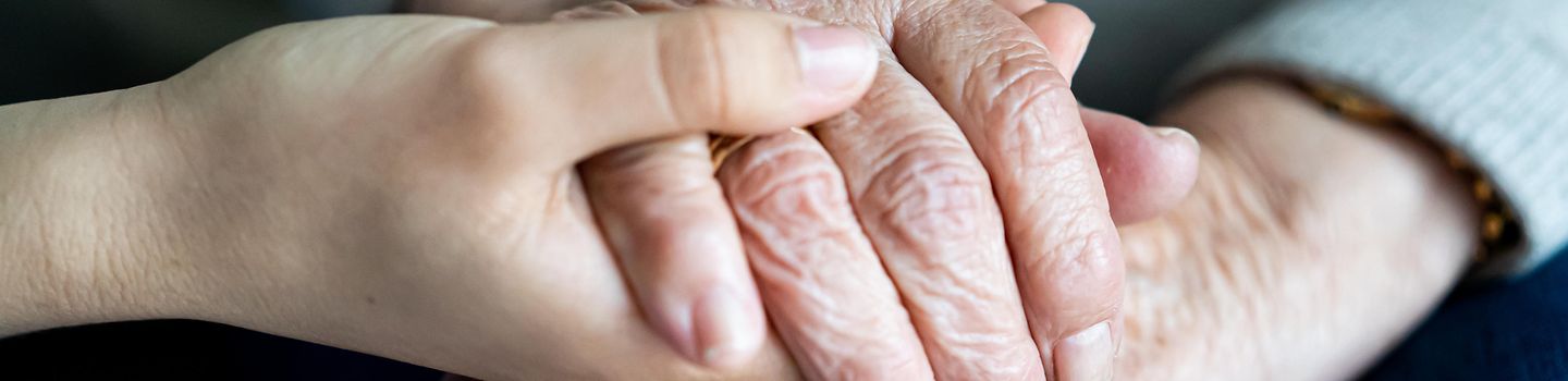 Eine junge Hand hält zwei alte Hände.