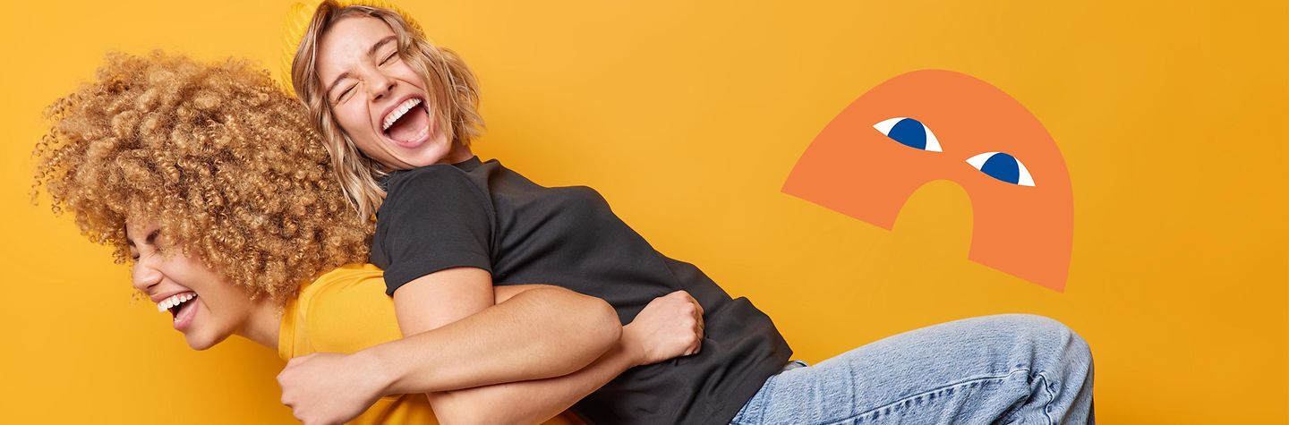 Zwei junge Frauen lehnen mit den Rücken aneinander, eine hebt die andere hoch. Sie lachen. Rechts von ihnen ist Flexi, ein orangener Bogen mit blauen Augen.