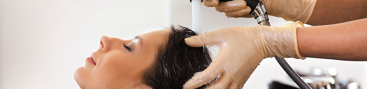 Friseurin wäscht Haare einer Kundin Einer Friseurkundin werden die Haare gewaschen