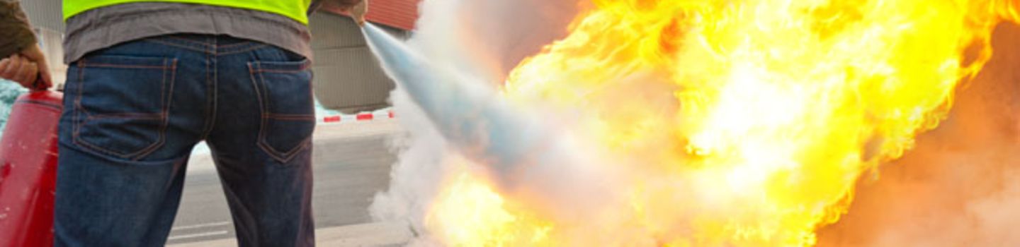 Brandschutz Ein Brandschutzhelfer löscht mit einem Feuerlöscher einen Brand