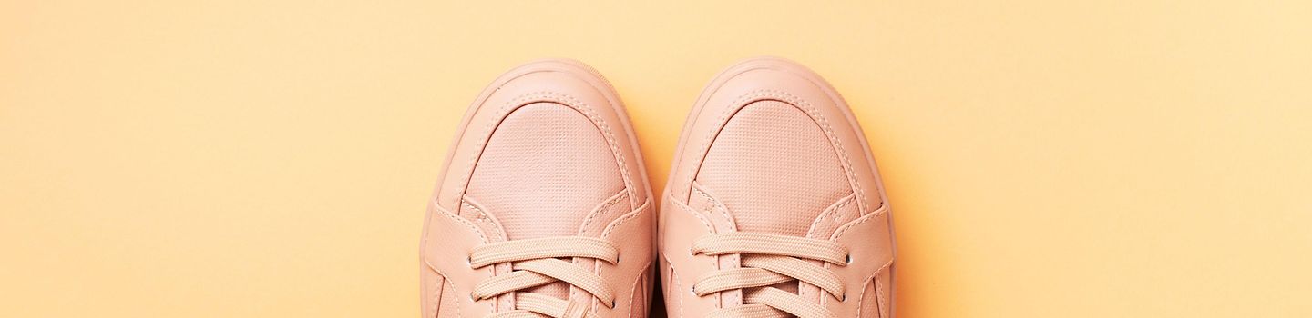 rosefarbene Sneaker vor gelbem Hintergrund
