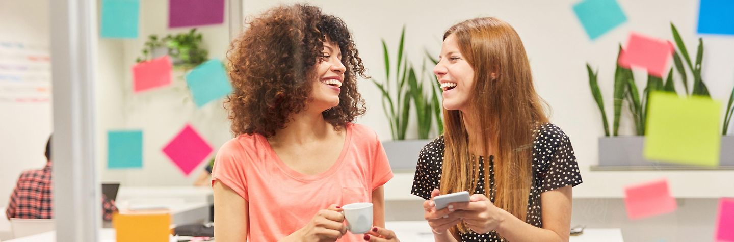 Zusammenarbeit Zwei junge Frauen als Business Trainees haben Spaß in einer Pause im kreativen Workshop